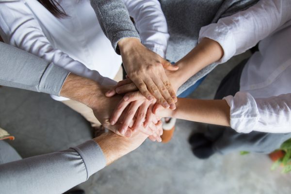 Four team members expressing togetherness and integrity. Closeup of stack of hands. Team concept